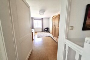 A hallway with a wooden wardrobe, a small table, and a chair. - Holiday home with 3 bedrooms (Wangerland)