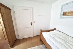 Une chambre à coucher avec un lit en bois, une porte blanche et un tableau encadré accroché au mur.