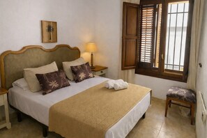 A neatly made bed with a wooden headboard, a bedside lamp, and a window with wooden shutters. - The individual Arona Mansion (Arona Casco)