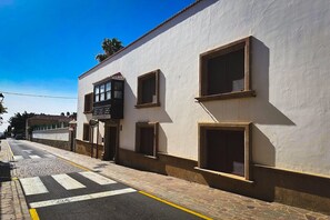 A street view with a white building featuring multiple windows and a pedestrian crossing. - The individual Arona Mansion (Arona Casco)