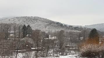 Un paysage enneigé avec une colline, des arbres et un bâtiment qui se dessine au loin.