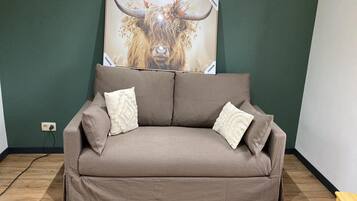 A brown sofa with two pillows against a green wall, with a bull painting above it.