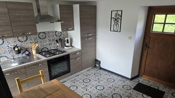 Una cucina compatta con piano cottura a gas, lavello e tavolo con sedie.