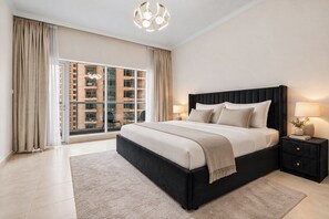 Ein modernes Schlafzimmer mit einem großen Bett, einem Nachttisch, einer Lampe und Blick auf ein Gebäude durch das Fenster.