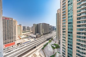 A high-rise building with multiple floors, a large parking area, and a busy road with vehicles. - StayShort - Elegant 1-Bedroom Stay in Downtown Dubai, Steps from Dubai Mall (Business Bay)