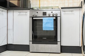 Eine Küche mit Edelstahlbackofen, weißen Schränken und einer gefliesten Spritzschutzwand.