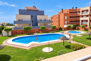A hotel with a swimming pool, a well-maintained lawn, and a clear view of the sea. - Coastal Family Apartment in Roquetas de Mar (Roquetas de Mar)