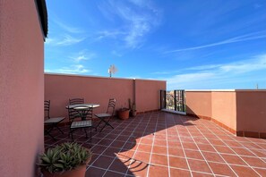 A terrace with a table and chairs, potted plants, and a view of the sky. - Coastal Family Apartment in Roquetas de Mar (Roquetas de Mar)