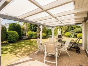 An outdoor patio with a brick floor, white furniture, and a stone pizza oven. - Holiday Home in Renesse With Swimming Pool (Renesse)