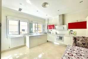 A modern kitchen with a central island, a microwave, and a red cabinet. - Central Granada Apartment for 4 (Granada)