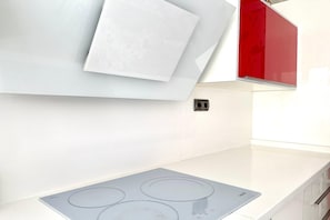 A kitchen with a white countertop, a built-in induction cooktop, and a red cabinet. - Central Granada Apartment for 4 (Granada)