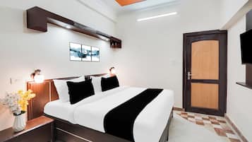 A hotel room with a bed, bedside tables, a wall-mounted TV, a door, and a ceiling light fixture.
