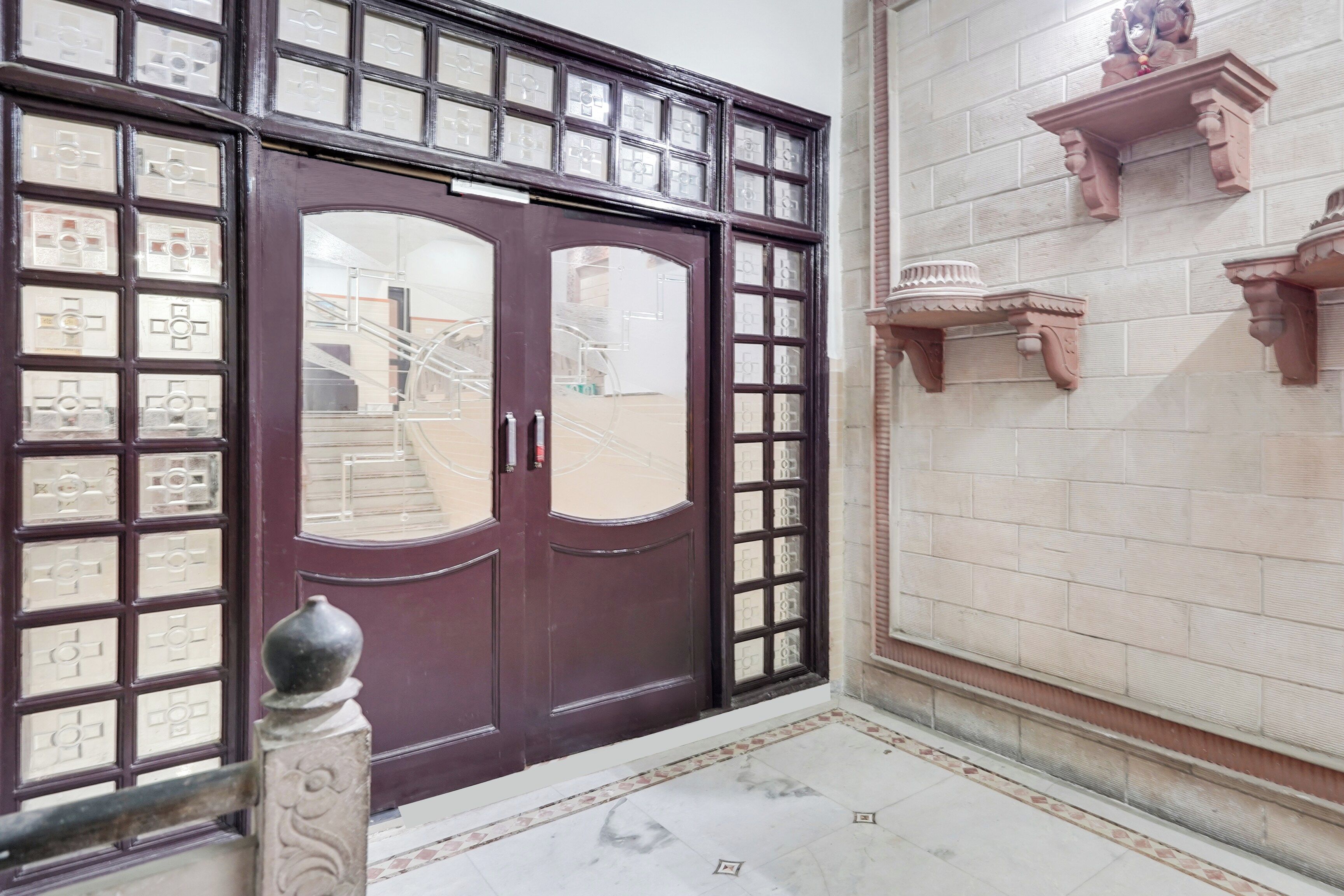 A double door with a grid pattern, a tiled floor, and a wall-mounted shelf with a decorative item.