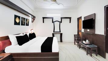 A hotel room with a bed, a desk, a chair, a television, and a ceiling fan.