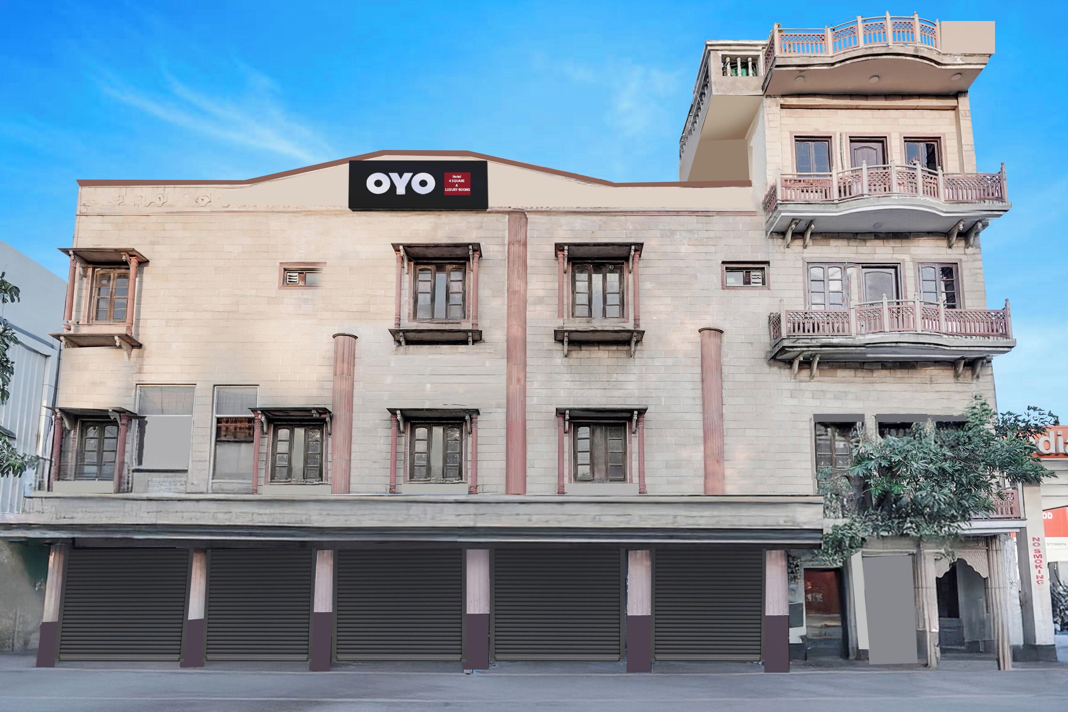A hotel with a sign reading 'OYO Hotel 4 SQUARE LUXURY ROOMS' and a balcony with ornate railings.