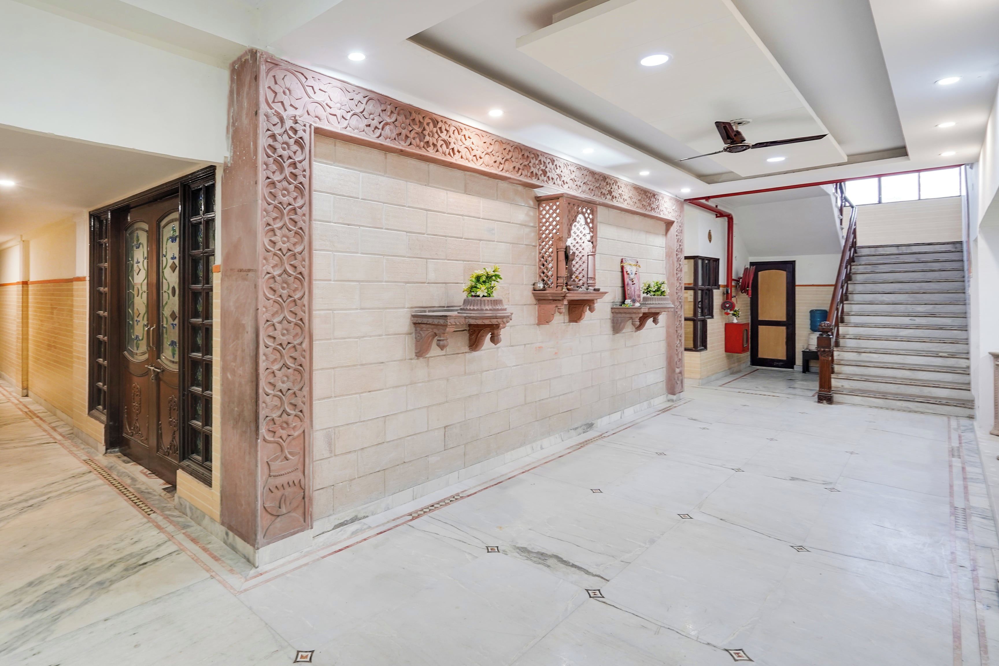 A spacious hallway with a marble floor, a decorative wall with intricate patterns, and a door with glass panels.