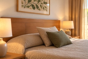 A neatly made bed with a textured blanket and two pillows, flanked by bedside lamps on wooden nightstands. - Romantic Apartment Getaway by the Beach (Pals)