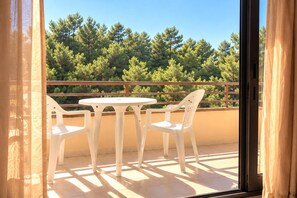 Ein Balkon mit Tisch und Stühlen, einem Holzgeländer und Blick auf Bäume.