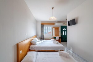 Habitación de hotel con dos camas, televisión y vista al mar.