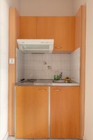 Cocina compacta con armarios de madera, estufa integrada y salpicadero de azulejos.