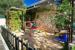 Un patio de recreo al aire libre con una estructura para escalar, un tobogán y una mesa pequeña.