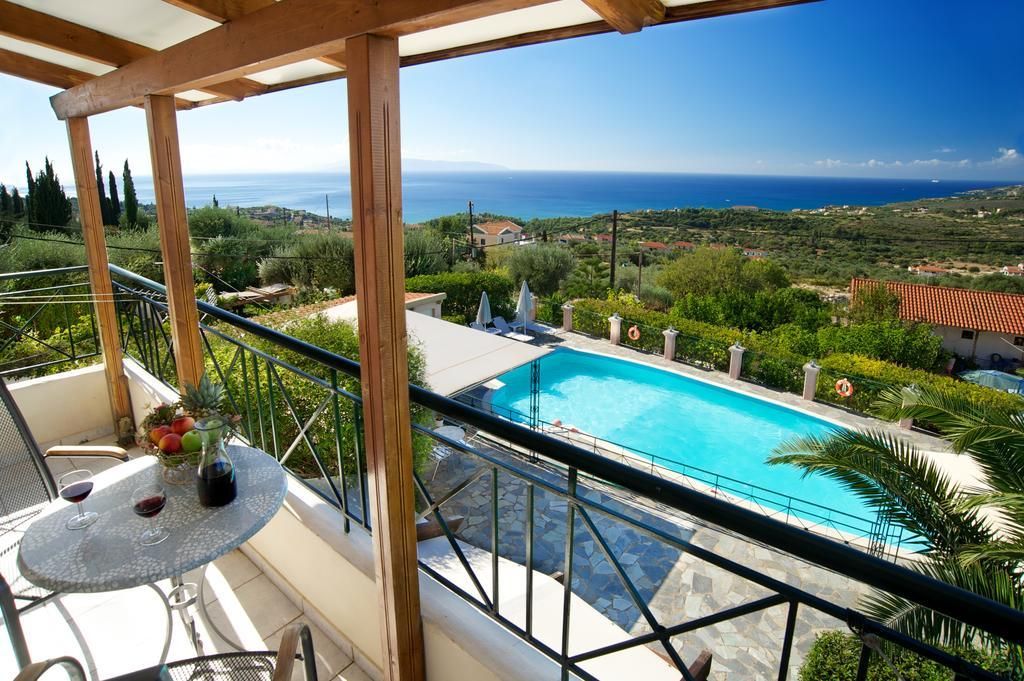 En balkon med udsigt over en swimmingpool og havet.