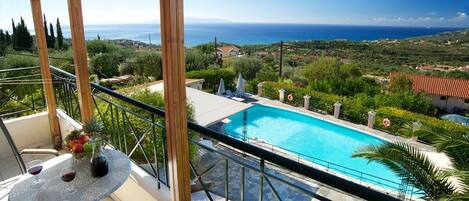 En balkon med udsigt over en swimmingpool og havet.