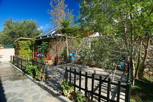 Un muro de piedra, un jardín cercado y un parque infantil con una estructura para escalar.