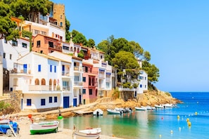 A coastal town with colorful buildings, a clear blue sea, and boats docked along the shore. - Coastal Family Apartment with Pool (Pals)