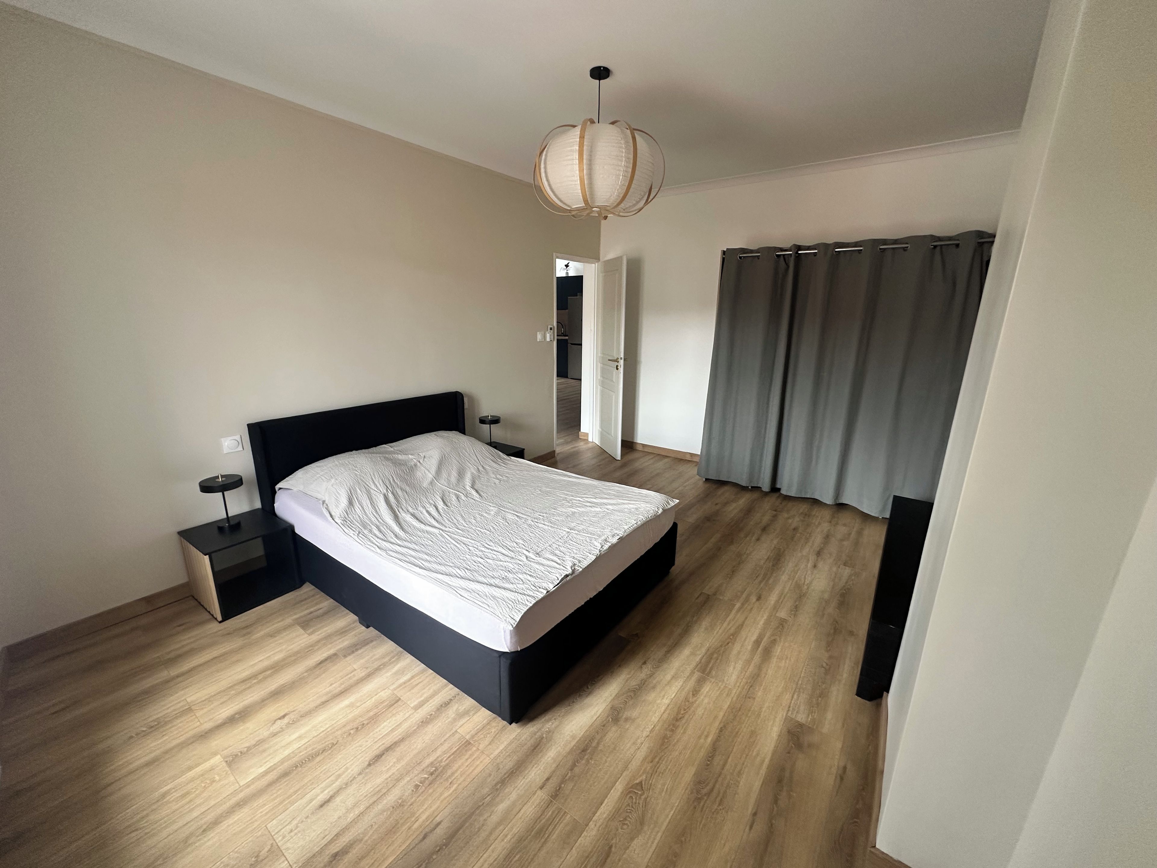 Une chambre à coucher avec un lit, une table de chevet et un luminaire suspendu.