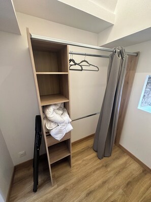 Een inloopkast met houten planken, een kledingroede en een douchegordijn.
