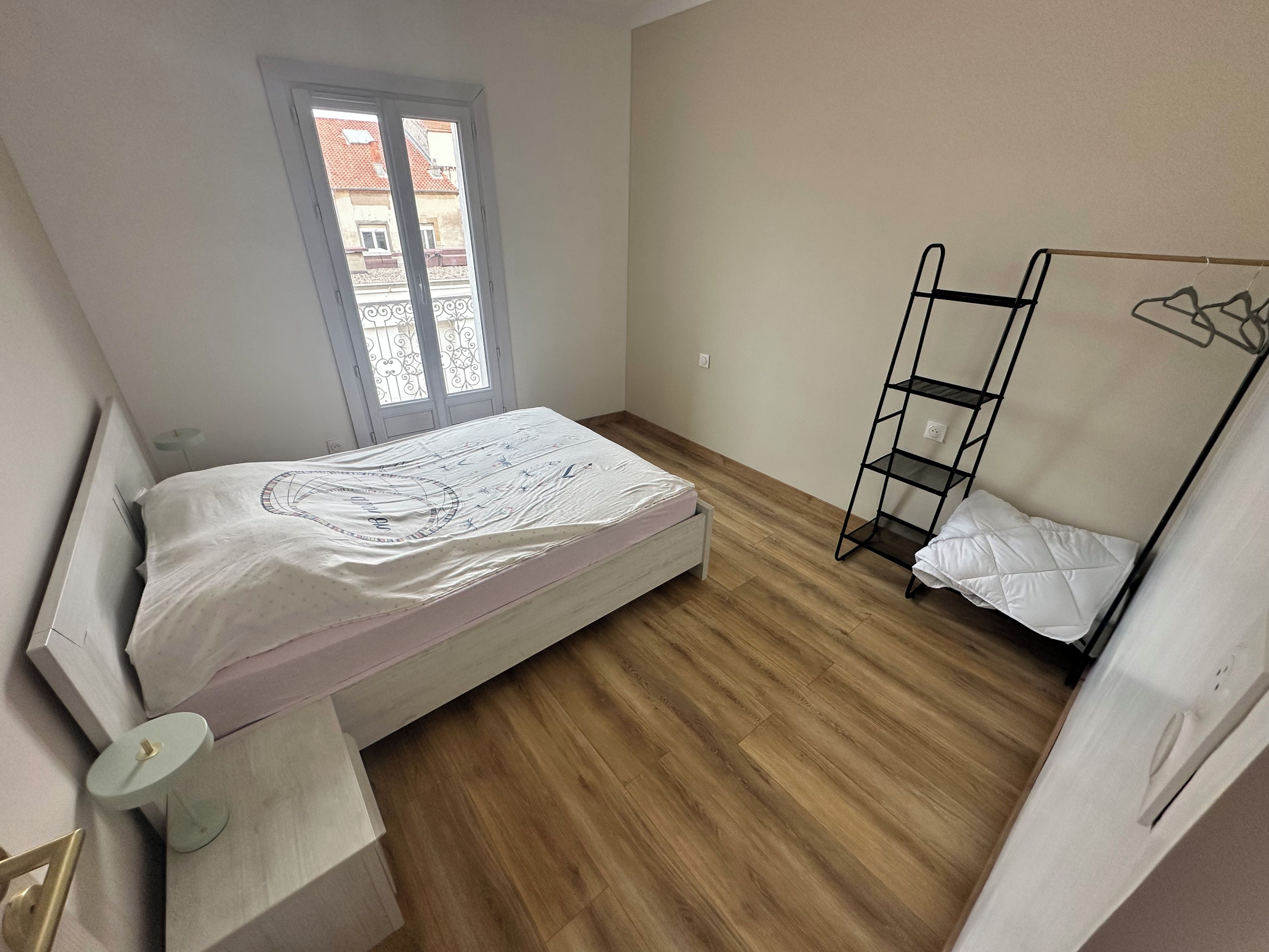 Une chambre avec un lit, une fenêtre, un lit superposé et une table de chevet.