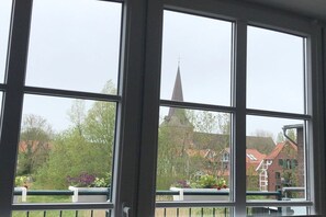 A view through a window with a view of a church steeple and residential buildings. - Holiday apartment with 1 bedroom (Otterndorf)