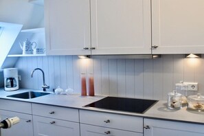 A modern kitchen with white cabinetry, a double sink, a built-in stovetop, and a coffee maker. - in the country house Arnfried, upper floor (Wenningstedt)