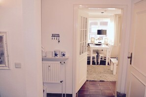 A hallway leading to a dining area with a white table and chairs, a radiator, and a wall-mounted decoration. - in the country house Arnfried, upper floor (Wenningstedt)