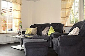Ein Wohnzimmer mit Ecksofa, Couchtisch und Heizkörper.