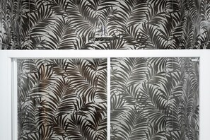 Una habitación con papel tapiz estampado y una ventana con marco blanco.