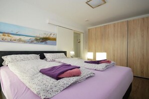 Une chambre d’hôtel avec un lit, un tableau, une armoire et une table de chevet avec une lampe.
