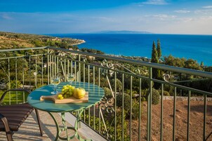 Un balcón con una mesa dispuesta para dos personas, con vistas a un paisaje costero.