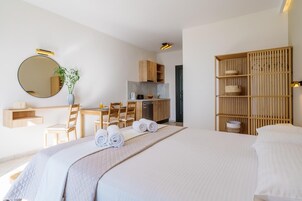 Una habitación de hotel moderna con una cama grande, un escritorio, una silla, una mesa de comedor y una cocina.