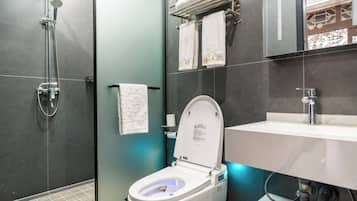 A modern bathroom with a toilet, shower, and sink.