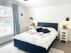 A bedroom with a bed, two bedside tables, a window with curtains, and a radiator. - Do10 Apartment in the Center of Domburg (Domburg)