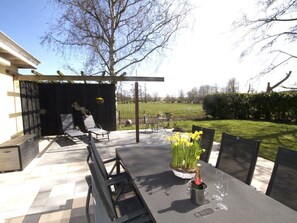 Eine Terrasse im Freien mit Tisch, Stühlen und einer Champagnerflasche.