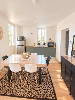 Eine moderne Küche mit Essbereich, inklusive Kühlschrank, Mikrowelle und großem Fenster.