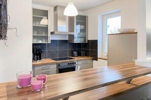 A modern kitchen with a wooden countertop, a built-in oven, and a coffee maker. - Holiday apartment with 1 bedroom (Timmendorfer Strand)