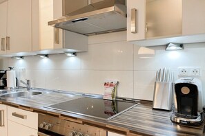 A modern kitchen with a built-in stove, a coffee maker, and a set of knives on the counter. - Holiday apartment with 1 bedroom (Timmendorfer Strand)