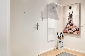 Un passadís amb una porta, una obra d'art penjada a la paret i un suport amb paraigües.