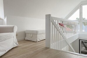 A room with a white bed, a white bench, and a white gate leading to a balcony. - Holiday apartment with 2 bedrooms (Timmendorfer Strand)