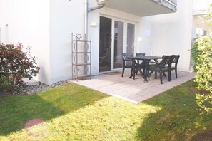 A patio with a table and chairs, a metal gate, and a small garden area. - Holiday apartment with 1 bedroom (Timmendorfer Strand)