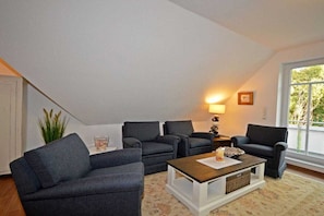 Un salon avec un plafond haut, deux canapés, une table basse et une lampe.